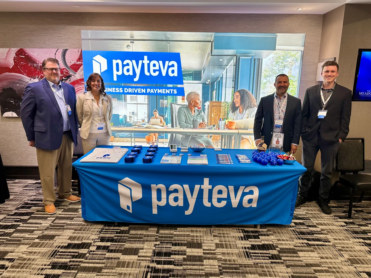 Four Payteva representatives at a professional conference booth with prominent Payteva branding